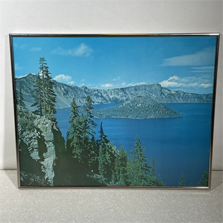 Photo of Crater Lake with pine trees in the foreground and a chrome metal frame